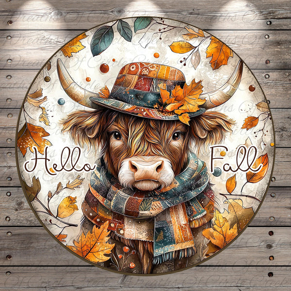 A cow wearing a colorful hat and scarf, surrounded by autumn leaves and the text "Hello Fall" in a circular design.