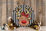 A decorative wreath featuring a red-nosed reindeer with a bow, surrounded by flowers and placed on a wooden surface.