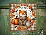 The image is a decorative wreath featuring a fox wearing a sweater and surrounded by autumn elements such as pumpkins, leaves, and flowers. The fox is sitting on a shelf with a cup of coffee and a book.