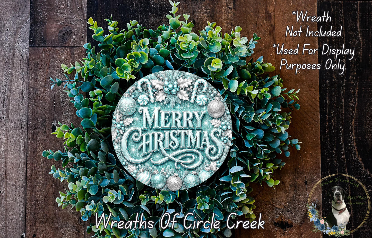 A wreath made of green leaves and a circular sign with the text "Merry Christmas" on it, placed on a wooden surface.