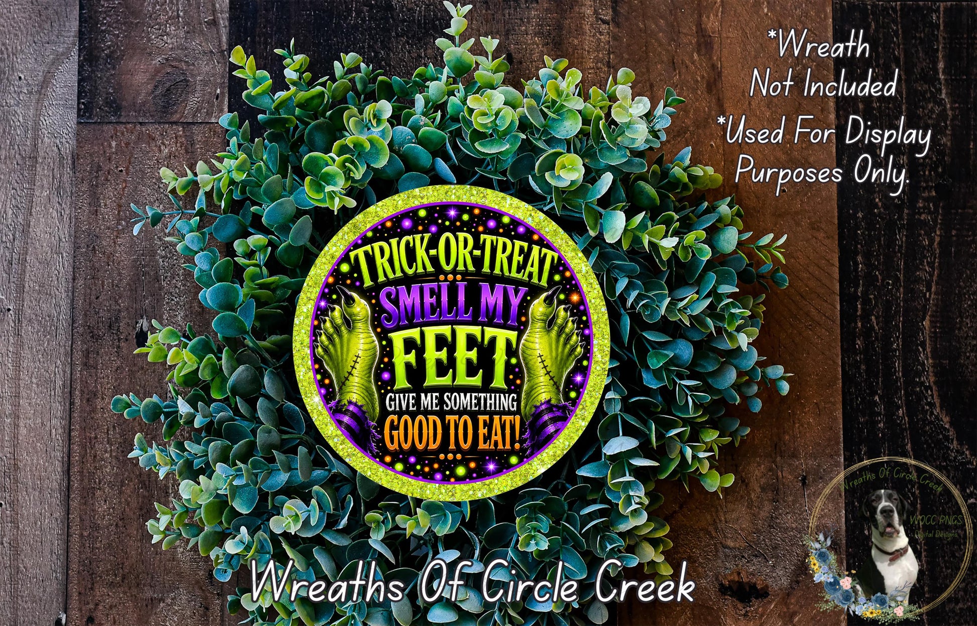a wreath made of green leaves and a purple and yellow sign that says "Trick or Treat Smell My Feet Give Me Something Good to Eat!" The sign is surrounded by the wreath, which is placed on a wooden surface.