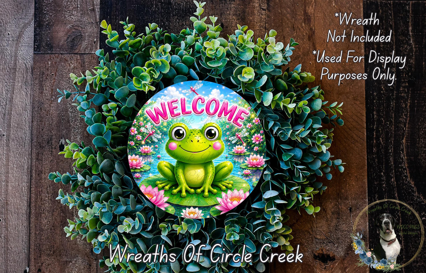 a wreath with a frog sitting on a pond surrounded by greenery. The wreath is placed on a wooden surface, and there is a text overlay that reads "Welcome Wreath Not Included * Used For Display Purposes Only" and "Wreaths of Circle Creek".