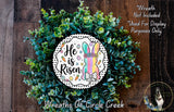 a wreath made of green leaves and flowers, with a decorative Easter bunny design in the center. The wreath is placed on a wooden surface, and there is a text overlay that reads "He is risen" and "Wreath Not Included * Used For Display Purposes Only".