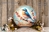A wooden sign with a blue bird perched on a branch, surrounded by flowers and greenery, with the word "WELCOME" displayed on the sign.