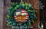 A wreath made of green foliage and two beer glasses with an American flag design, placed on a wooden surface.