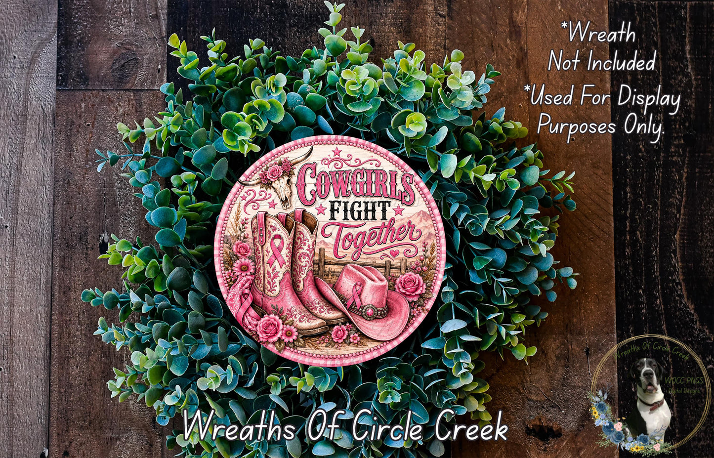 a wreath made of green leaves and a pink cowboy boot with the text "Cows fight together" on it. The wreath is displayed on a wooden surface, and there is a small dog in the bottom right corner of the image.