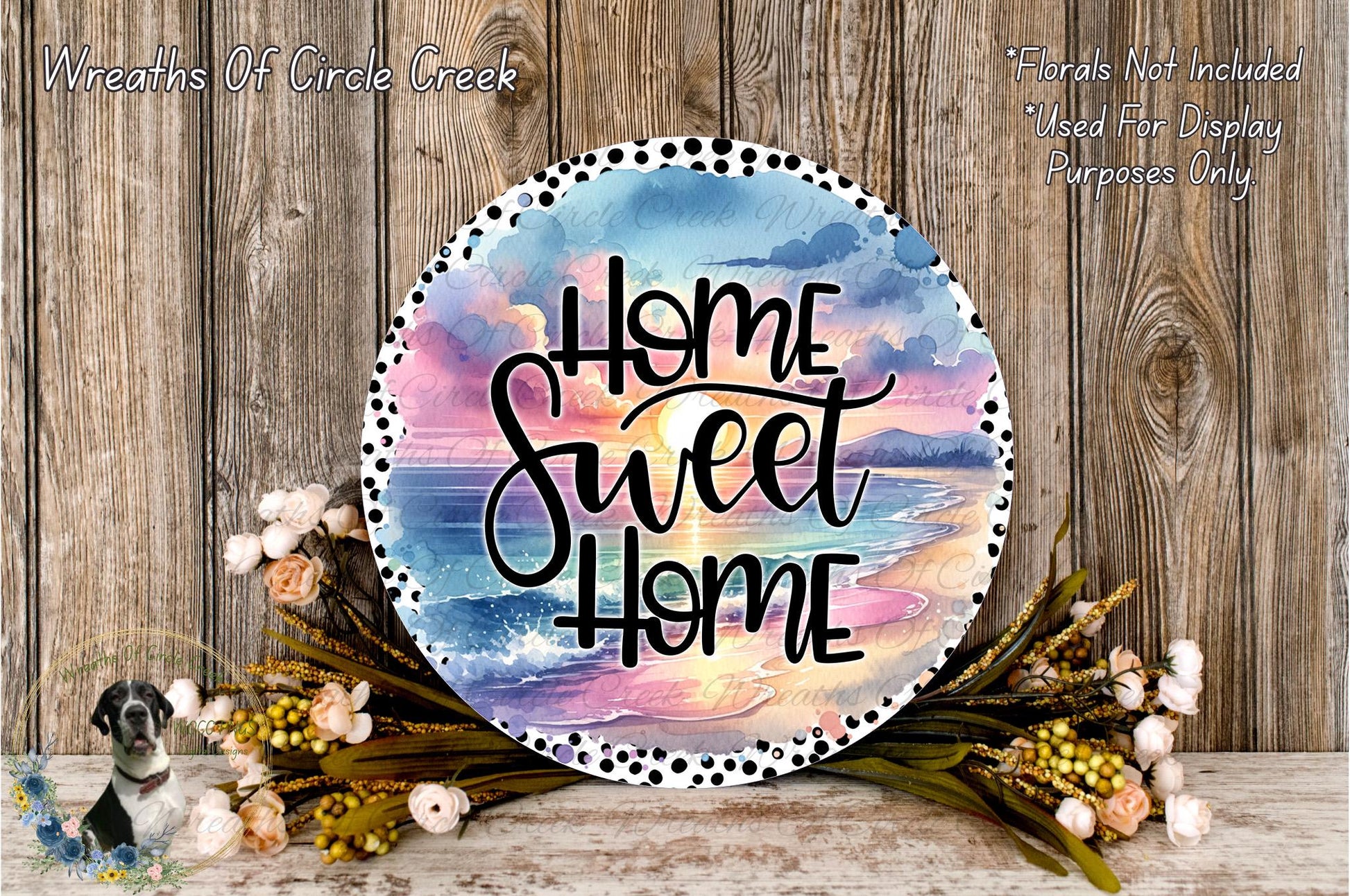 a decorative sign with the text "Home Sweet Home" against a backdrop of a colorful sunset and beach scene. The sign is surrounded by a floral arrangement and placed on a wooden surface.