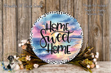 a decorative sign with the text "Home Sweet Home" against a backdrop of a colorful sunset and beach scene. The sign is surrounded by a floral arrangement and placed on a wooden surface.