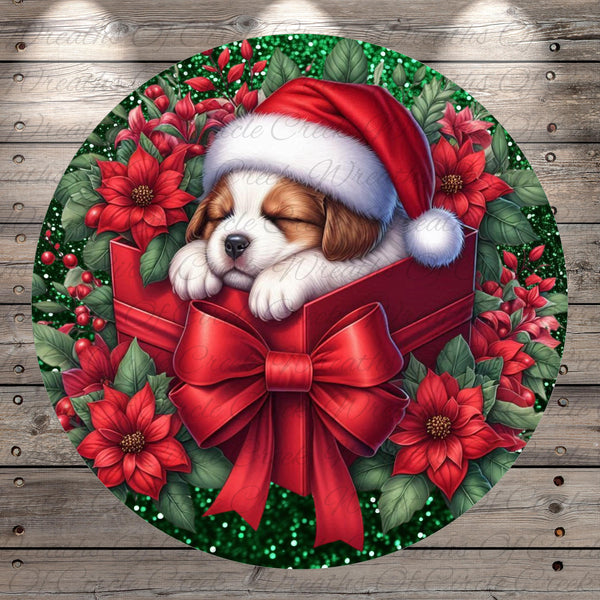 A sleeping puppy wearing a Santa hat is nestled in a red gift box, surrounded by red poinsettia flowers and green leaves, creating a festive Christmas wreath.