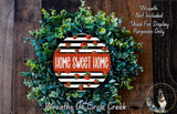 a wreath made of green and white leaves, with a red and white circular design in the center that says "Home Sweet Home".
