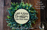 a wreath made of green leaves and flowers, with a message that reads "Like a good neighbor, stay over there" in a checkered pattern.