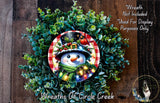A wreath featuring a snowman with a red scarf and a bird perched on its head, surrounded by a lush green wreath.