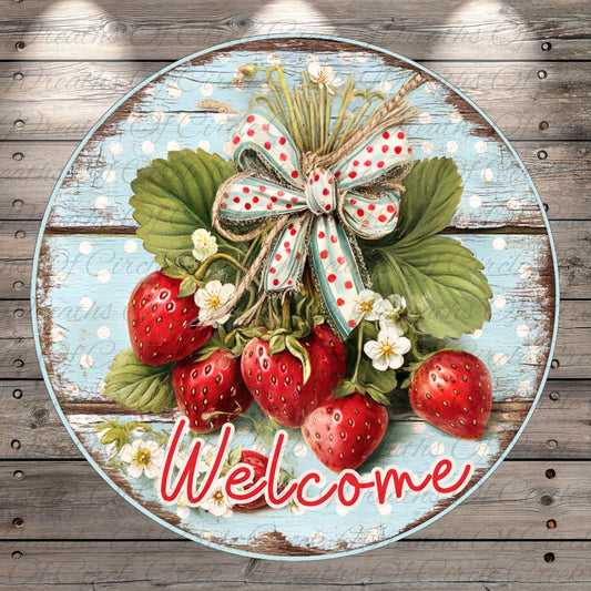 A circular wooden sign with a bow made of twine and flowers, surrounded by red strawberries and white flowers, with the word "Welcome" written in cursive below.