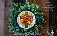 a wreath with a cross and a floral arrangement, placed on a wooden surface.