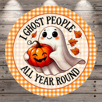 A round, orange and white sign with a cartoon ghost holding a pumpkin and the text "I ghost people all year round"