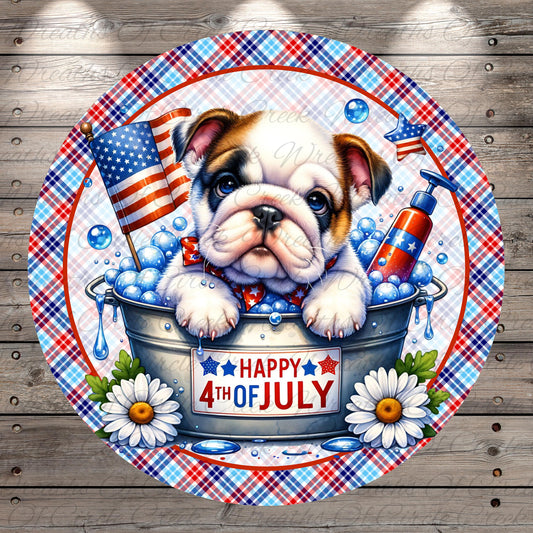 A bulldog is sitting in a bucket filled with bubbles, surrounded by American flags, daisies, and a "Happy 4th of July" sign.