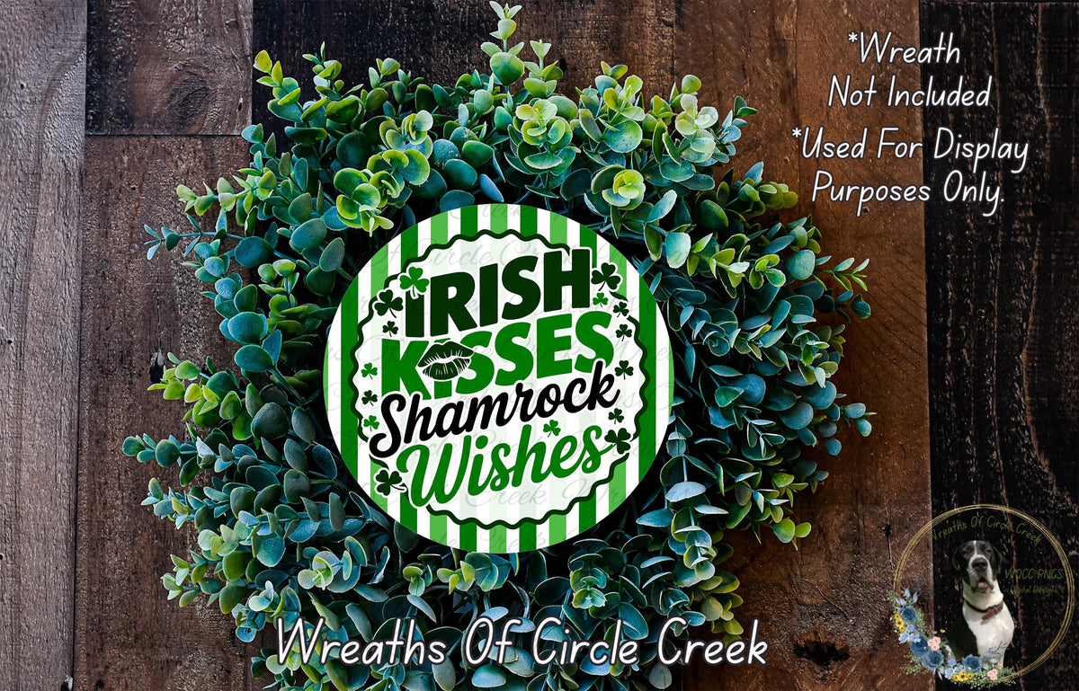 a wreath made of green leaves and flowers, with a circular sign in the center that says "Irish Kisses Shamrock Wishes".