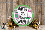 a decorative sign with the text "We're on the Course!" surrounded by a floral arrangement and a golf club.