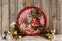 A decorative plate featuring a dachshund dog wearing a red scarf, surrounded by Christmas-themed elements such as a red and white striped border, pine branches, and a red ribbon.
