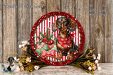 A decorative plate featuring a dachshund dog wearing a red scarf, surrounded by Christmas-themed elements such as a red and white striped border, pine branches, and a red ribbon.