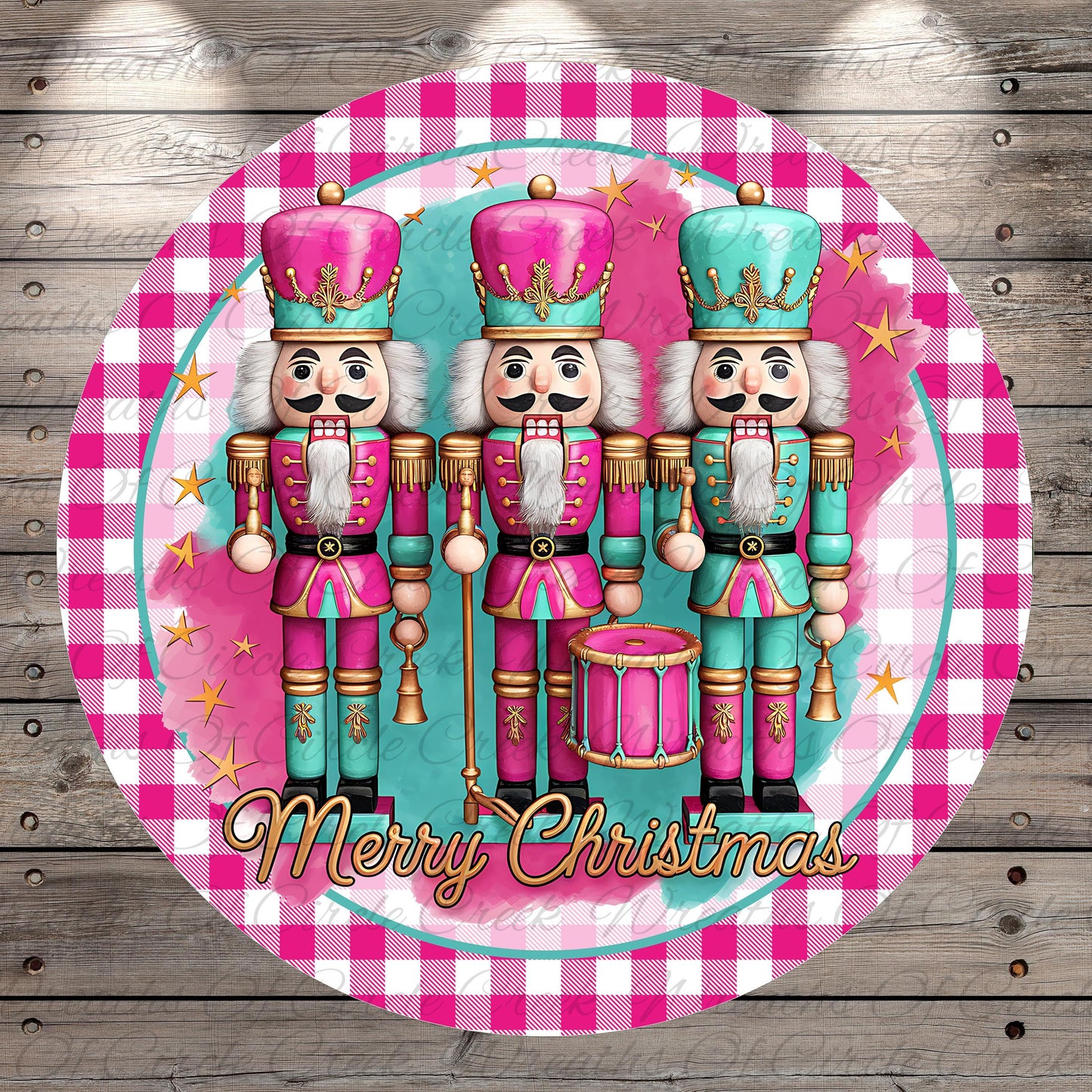 A circular design featuring three nutcracker characters in pink and teal outfits, standing in a row and holding a drum. The text "Merry Christmas" is displayed below the nutcracker characters.
