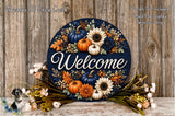 a decorative welcome sign with a floral design, surrounded by autumn-themed flowers and foliage. The sign is placed on a wooden surface, and there is a small bird figurine in the bottom left corner.