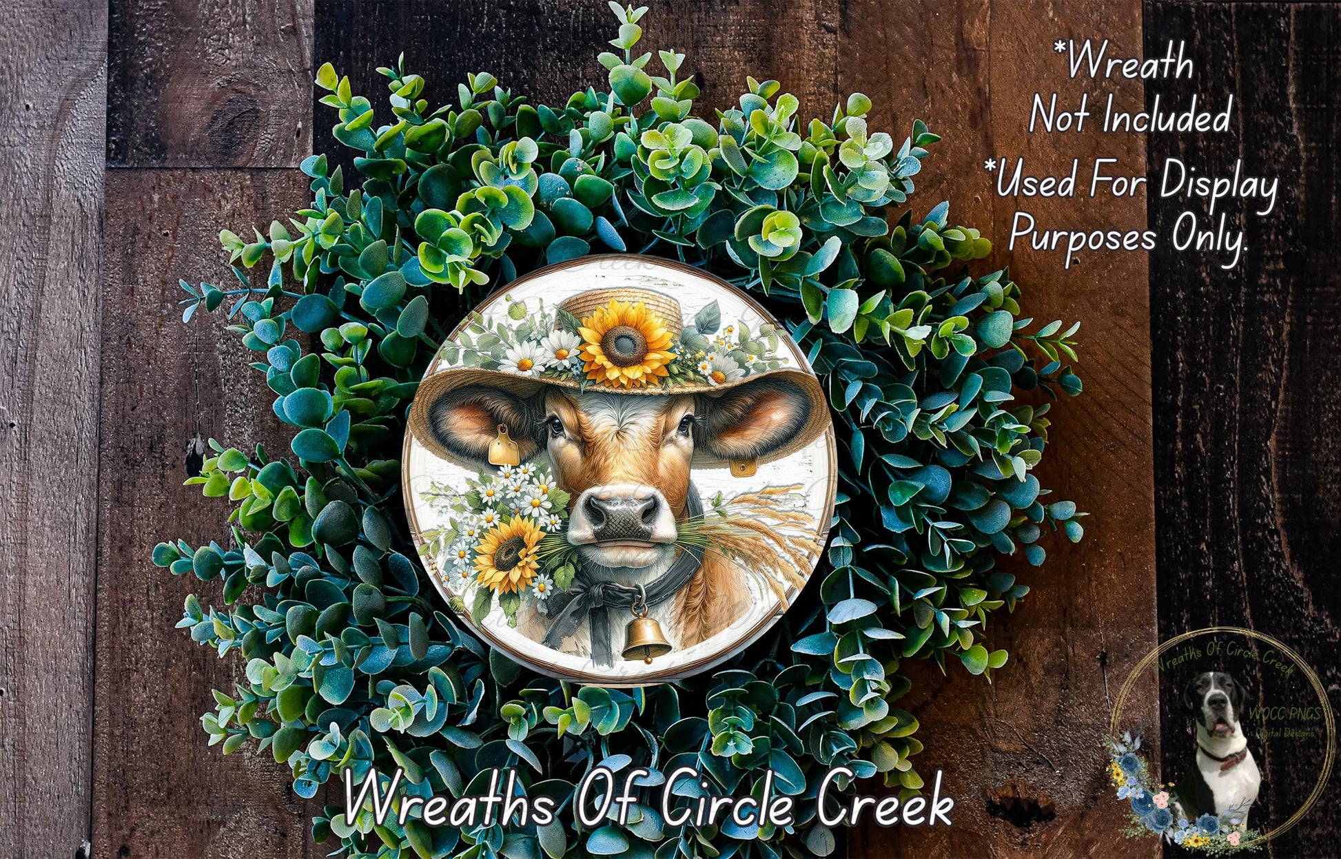 a wreath with a cow wearing a hat and surrounded by greenery, including sunflowers. The wreath is displayed on a wooden surface, and there is a small dog in the bottom right corner.