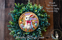 A wreath made of green leaves and flowers, with a wooden frame featuring a white rabbit and Easter eggs, and a text overlay that reads "Happy Easter" and "Wreath Not Included Used For Display Purposes Only".