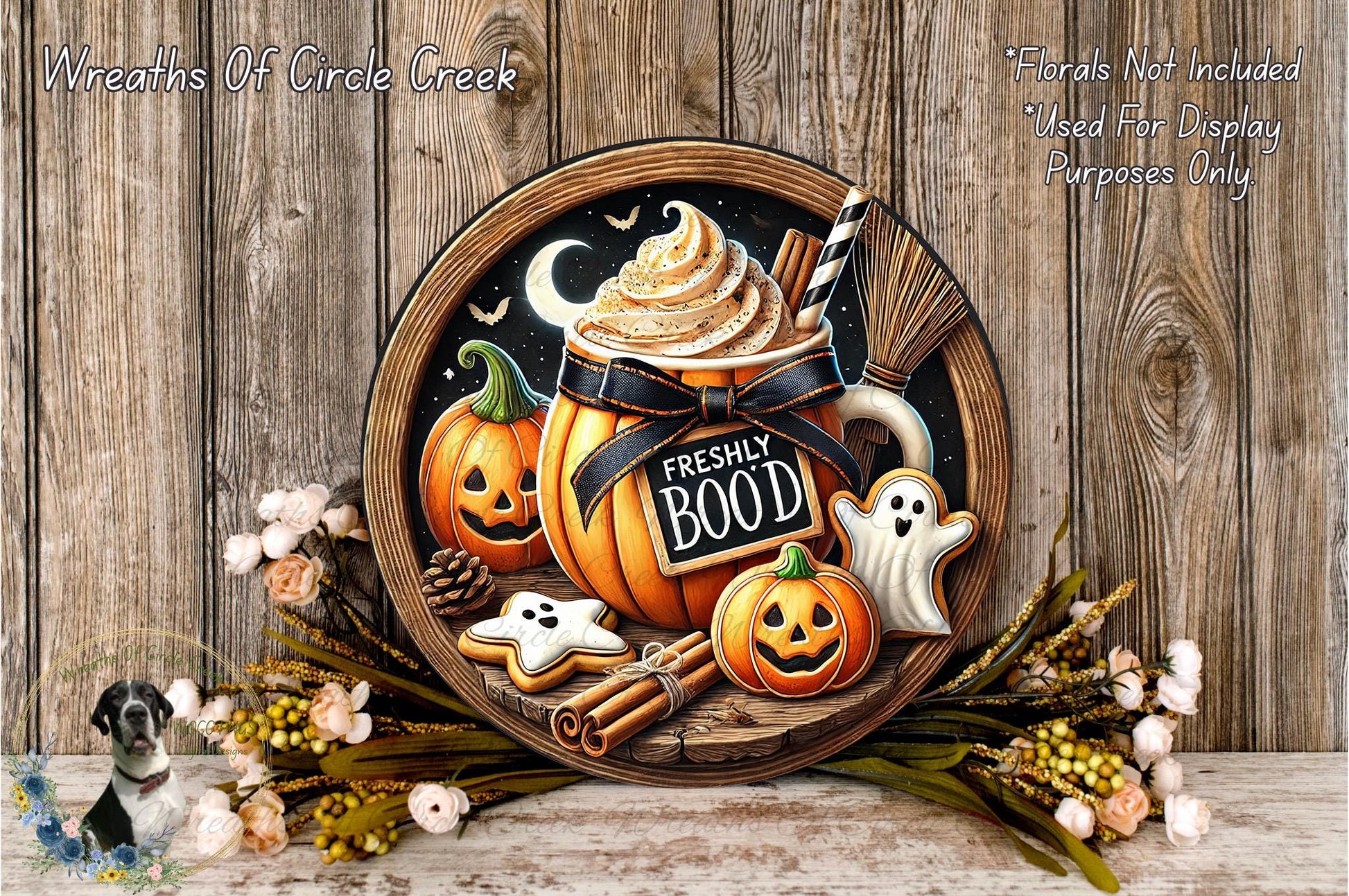 a Halloween-themed wreath with a pumpkin, ghost, and other spooky decorations, along with a mug of whipped cream and a sign that says "FRESHLY BOO". The wreath is displayed on a wooden surface, surrounded by flowers and other Halloween-themed items.