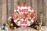 a decorative sign with the text "Sweet summer time" surrounded by flowers and greenery, placed on a wooden surface.