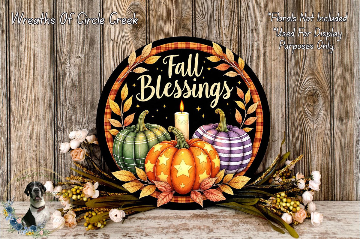 a decorative wreath with a central design of pumpkins and leaves, surrounded by flowers and a lit candle, all set against a wooden background.