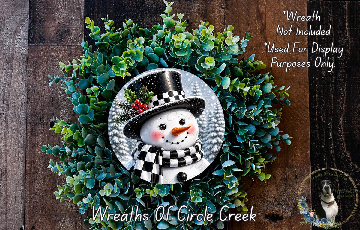 A wreath featuring a snowman made of green leaves and a black top hat, with a red bow on the snowman's face.