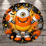 A whimsical, cartoonish monster with a large, round head, orange and white fur, and a big smile, surrounded by Halloween-themed elements such as candy, bats, stars, and a spiral.
