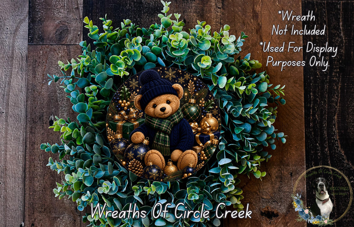 A wreath made of green leaves and a brown teddy bear wearing a blue scarf, with a wooden background.