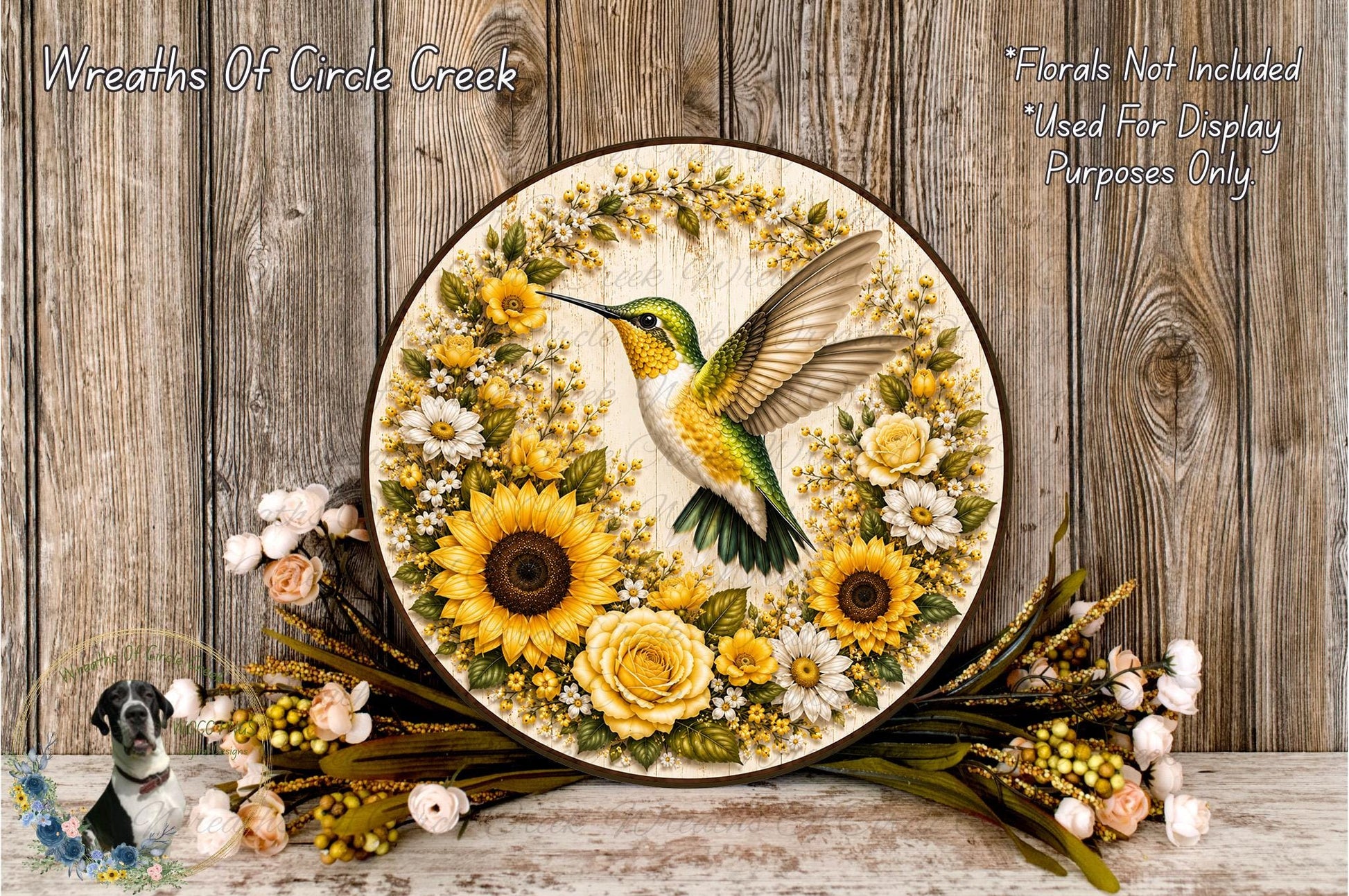 A decorative wreath featuring a hummingbird surrounded by sunflowers and other flowers, placed on a wooden surface.