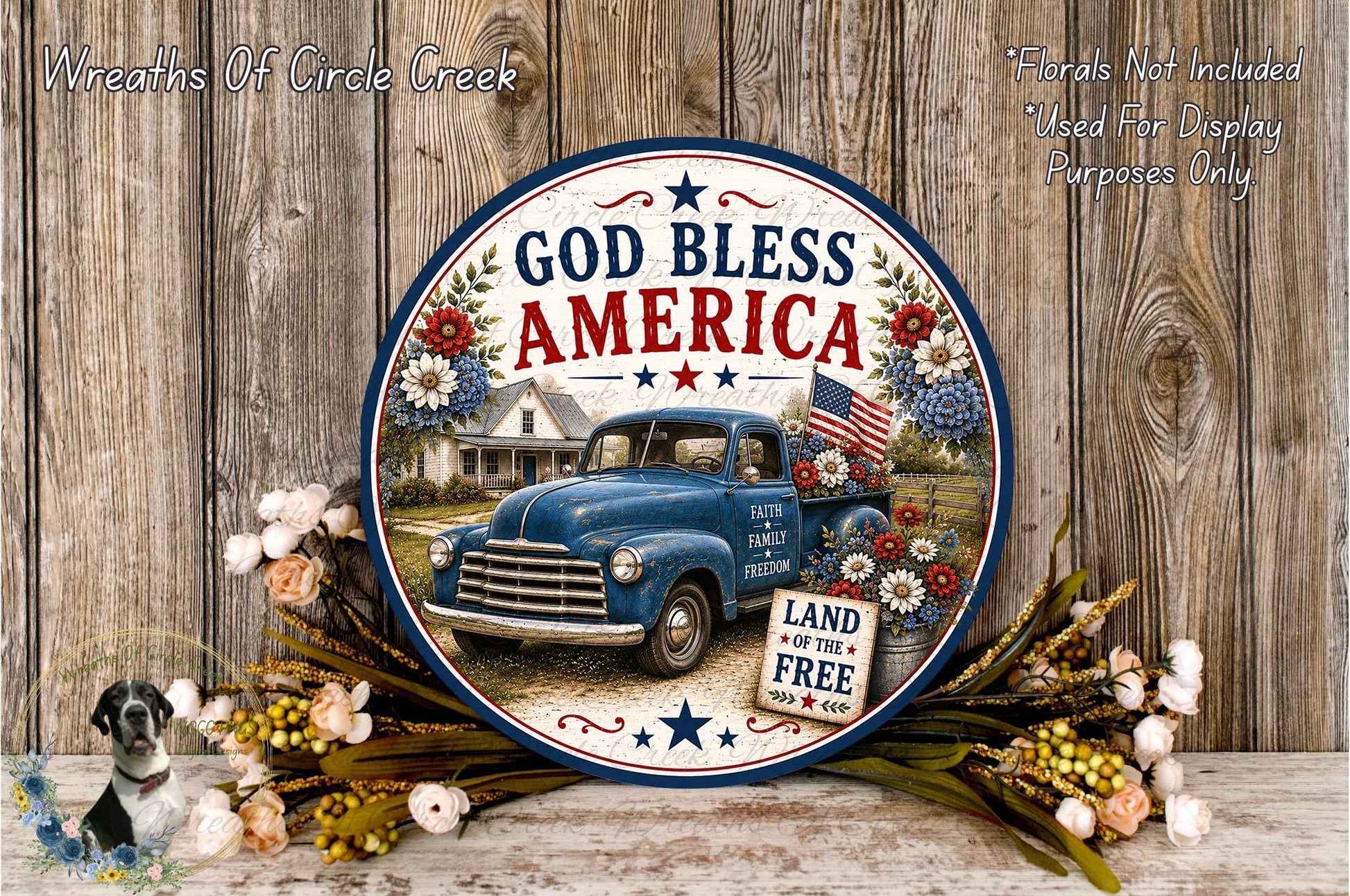 A round decorative plate with a vintage blue truck and patriotic imagery, surrounded by flowers and a wooden background.