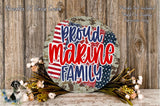 a patriotic-themed wreath with the text "Proud Marine Family" displayed prominently. The wreath is surrounded by a floral arrangement and is set against a rustic wooden background.