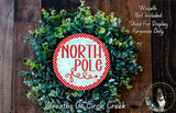 A wreath made of green leaves and a red and white circular sign that says "NORTH P Pole".