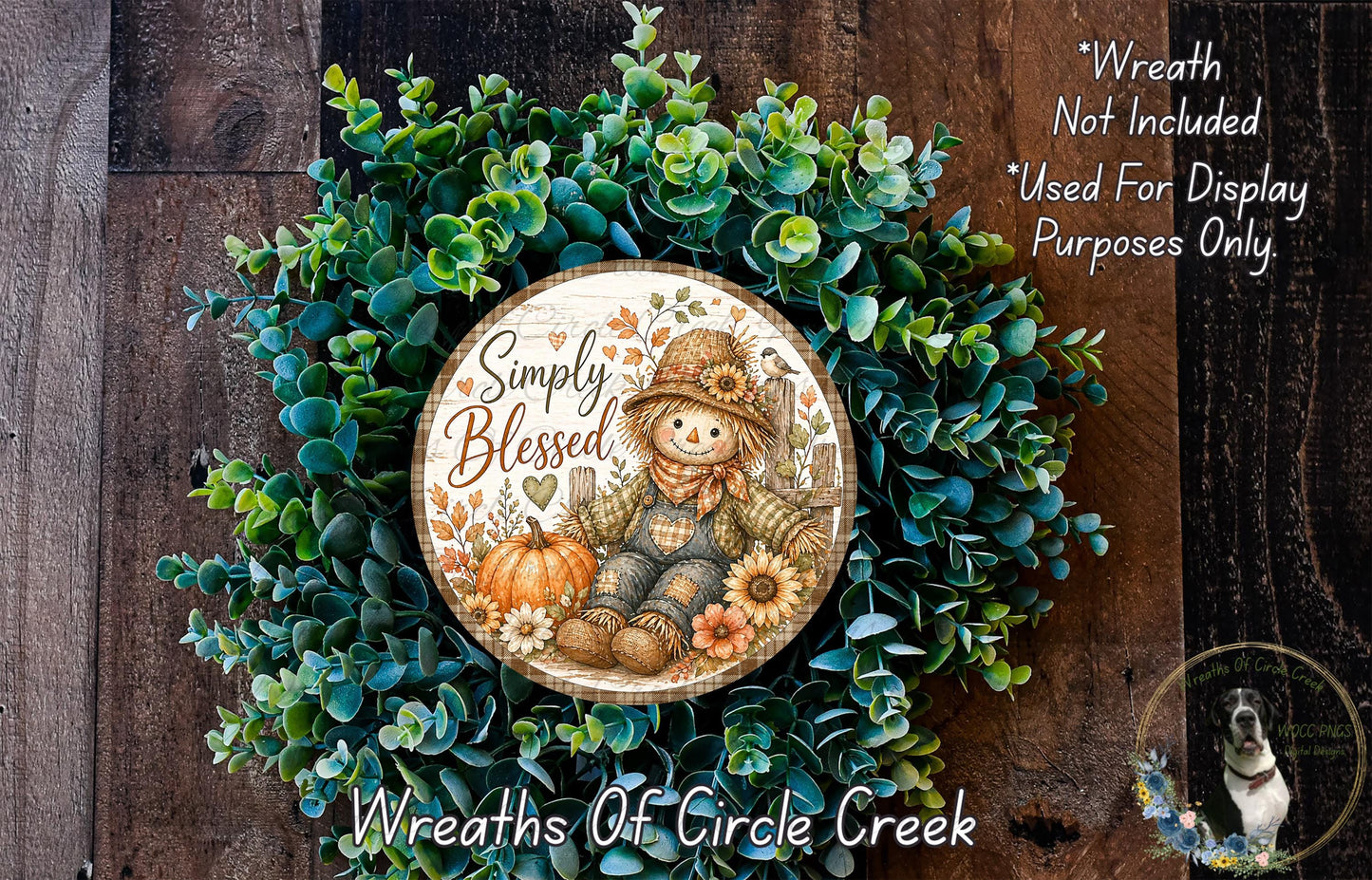 a wreath with a pumpkin and a scarecrow design, surrounded by greenery. The wreath has a circular plaque with a scarecrow and the text "Simply Blessed".