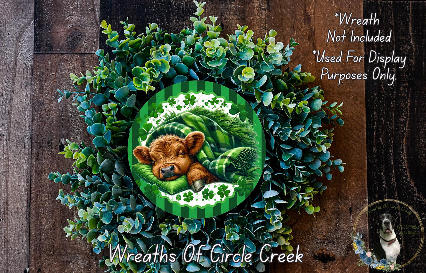 a wreath with a brown cow resting on it, surrounded by green foliage. The wreath is displayed on a wooden surface, and there is a small dog visible in the bottom right corner of the image.