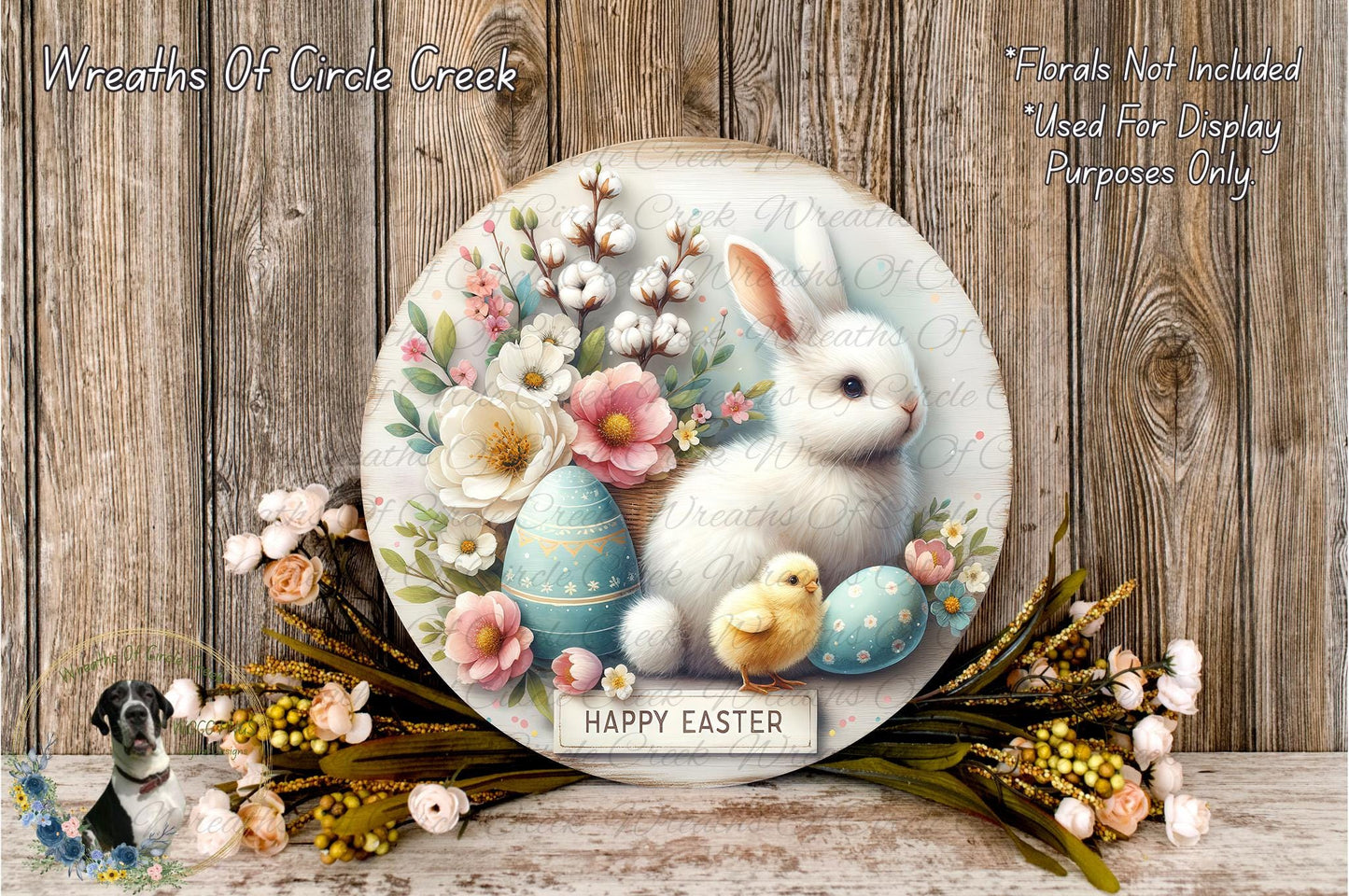 A round wooden plaque with a white rabbit, blue Easter eggs, and pink flowers, surrounded by a floral arrangement and a "Happy Easter" sign.
