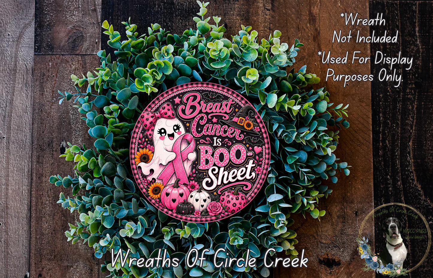 a wreath with a pink and black design, surrounded by green foliage. The wreath has a message about breast cancer, and there is a small dog in the background.