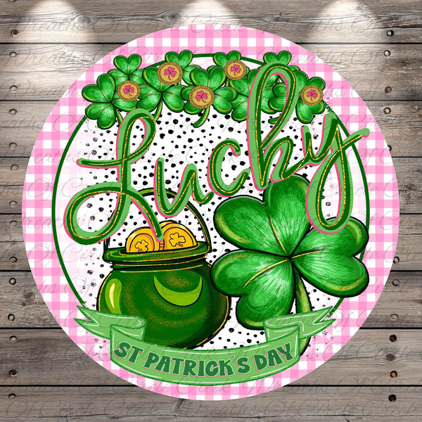 A circular design featuring a pot of gold coins, a clover, and the word "Lucky" written in cursive. The background is a pink and white checkered pattern.