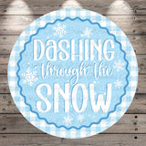 A circular sign with the text "DASHTING THROUGH THE SNOW" written in a decorative blue and white font, surrounded by snowflake-like designs.