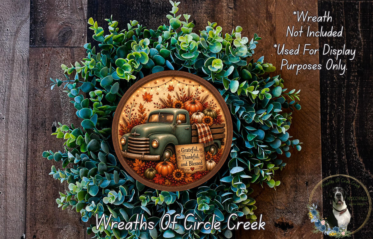 A wreath made of green leaves and a vintage green truck with pumpkins and fall foliage, along with a circular sign that reads "Grateful, Thankful and Blessed".
