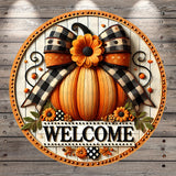 A decorative welcome sign featuring a large orange pumpkin with a bow, surrounded by flowers and leaves, with the word "WELCOME" displayed prominently.