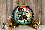 A round, decorative wreath with a woman dressed as a witch, holding a broom, surrounded by flowers and a wooden background.