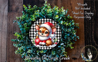 A wreath featuring a cartoon deer wearing a Santa hat, surrounded by green foliage.