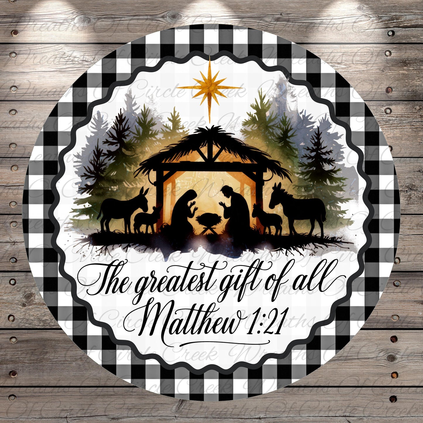 A circular design featuring silhouettes of a nativity scene with a man, woman, baby, and animals in a manger, surrounded by a forest and a star. The text "The greatest gift of all Matthew 1:21" is displayed below the nativity scene.