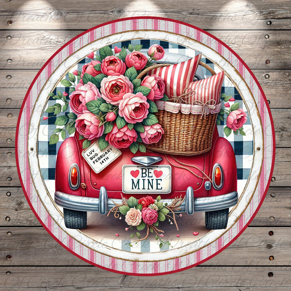 A vintage red car with a basket filled with pink roses, surrounded by a floral arrangement and a "Be Mine" sign.
